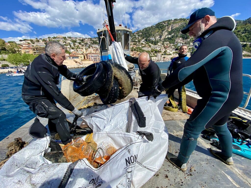 Des bénévoles rangent dans des sacs des déchets récoltés au fond de la rade à l'aide de la grue du bateau Pégase.