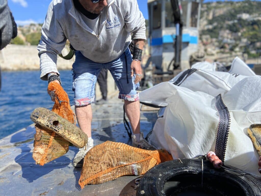 Un bénévole à bord du bateau Pégase range des déchets dans des grands sacs.